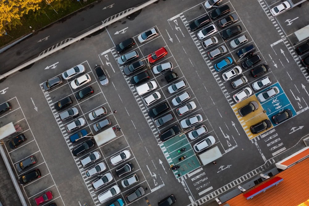 Aerial view of a large, organized asphalt parking lot filled with many colorful cars. Designated spaces, including for disabled drivers, plus clear white lane markings, showcase quality commercial asphalt work in Wilson County.